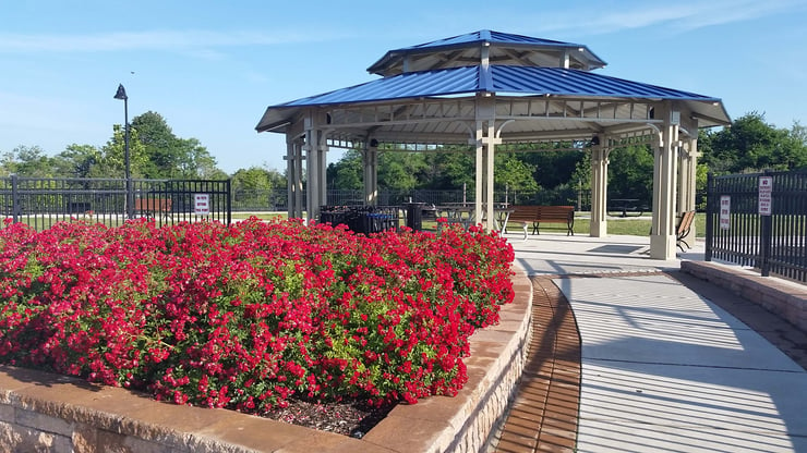 Large blue octagon shelter with benches surrounded by red flowers Lancaster, CA