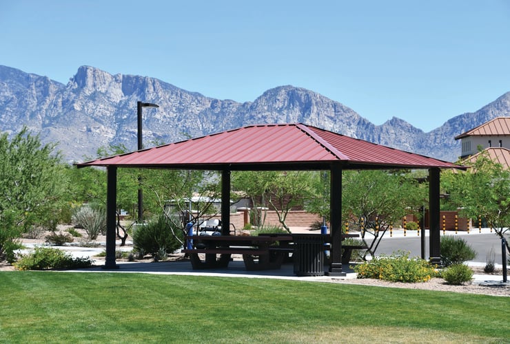 Red rectangular shelter with corrugated steel roof in Tuscon, AZ with mountains in the background.