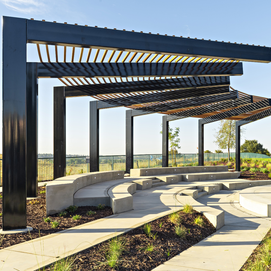 Large custom steel arbor structure with concrete amphitheater on a sunny day.